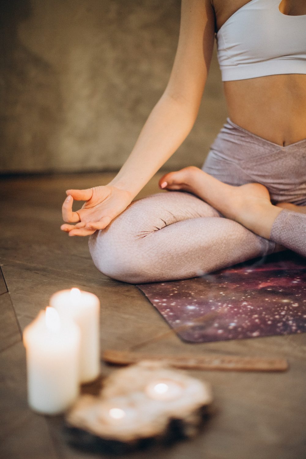 Mujer meditando sobre una alfombra, con velas encendidas, transmitiendo calma y equilibrio emocional, bienestar